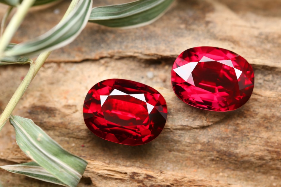 Red garnet gemstones with leaves in background.