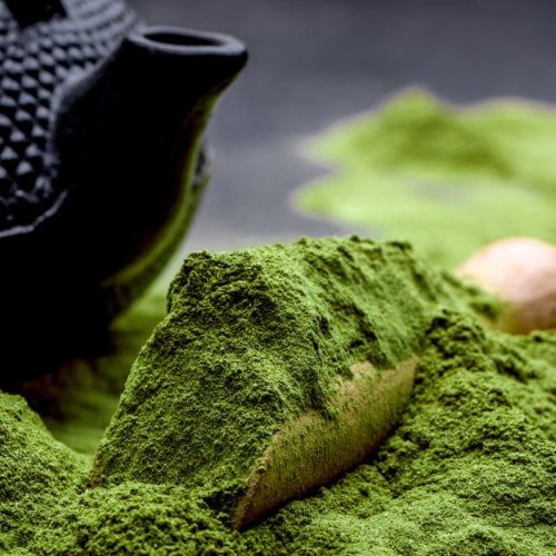 Powdered green tea and set for matcha on black background.