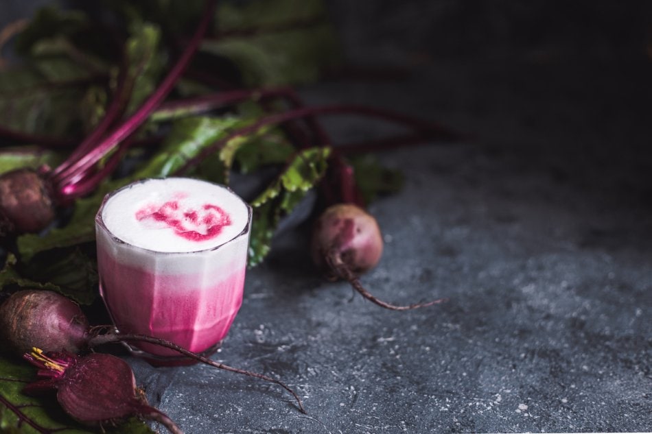 Beetroot latte. Healthy beetroot drink with whole beetroots on dark background with copy space.