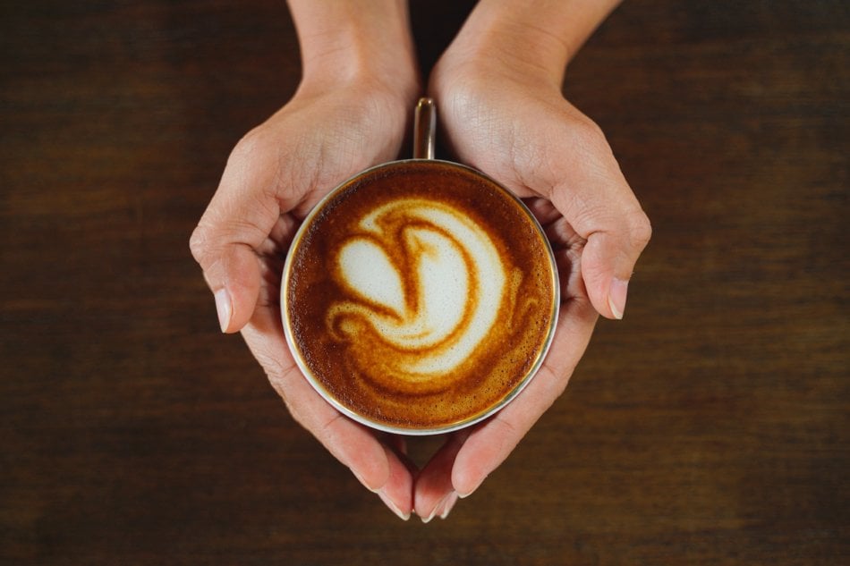 Woman's hands holding latte overhead view.