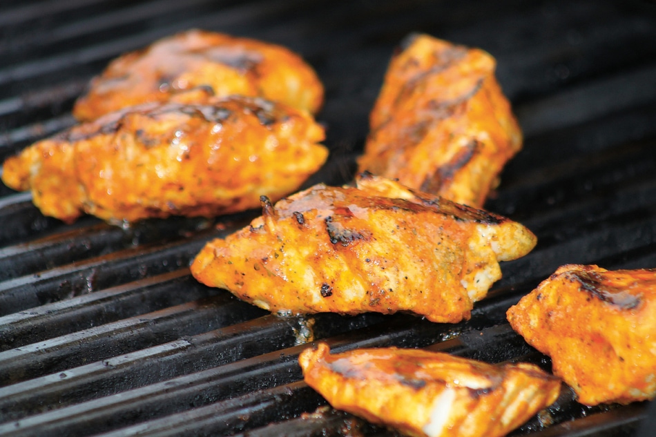 Small fillets of fish cooking on a grill.