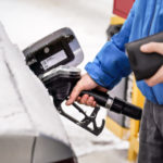 A feature image of a person putting fuel in their car wondering how to save money on gas this winter.