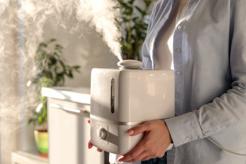 A woman using a humidifier to lower heating bill.