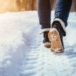 A man walking through the snow reviewing winter weather 2021-2022 forecasts.