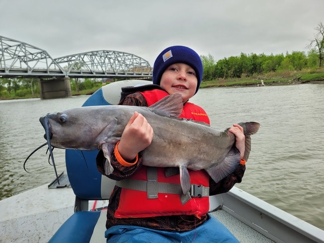 A boy showing his catfishing catch.