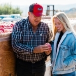 Experienced apple farmer Kaitlyn Thornton with her father looking at a cosmic crisp apple.