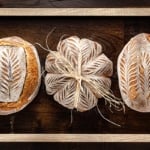 How to make sourdough starter represented by three loaves of sourdough bread.