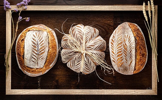 How to make sourdough starter represented by three loaves of sourdough bread.