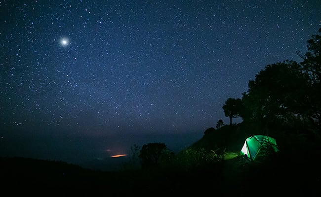 The North Star and many bright stars shining above a campsite