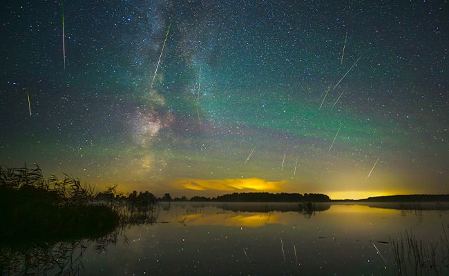Meteor showers tonight with shooting stars over a lake at sunset.