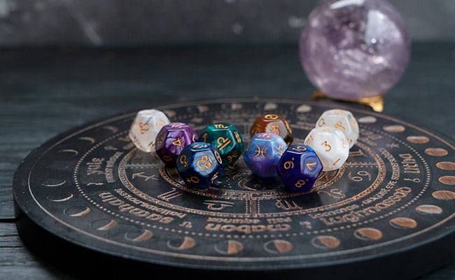 Full Moon Horoscopes represented by zodiac signs on dice and an amethyst crystal ball.