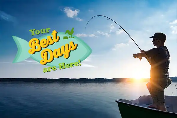 Silhouette of a man fishing from a boat in the ocean and the horizon in the distance.