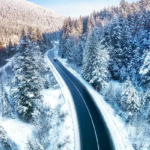 Farmers' Almanac winter 2025-2026 forecast represented by road with snowy trees and mountains.