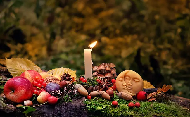 Fall equinox Mabon ritual with a burning candle, vegetables, and fruits.