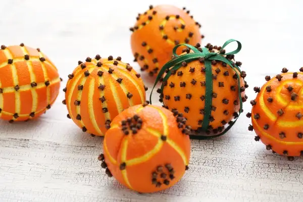 Pomanders made out of oranges and cloves. One pomander has a green ribbon tied around it.