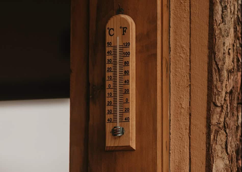 Wooden outdoor thermometer showing temperature in Celsius and Fahrenheit.
