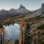 Scenic mountain landscape with lake, trees, and rocky peaks in fall colors.