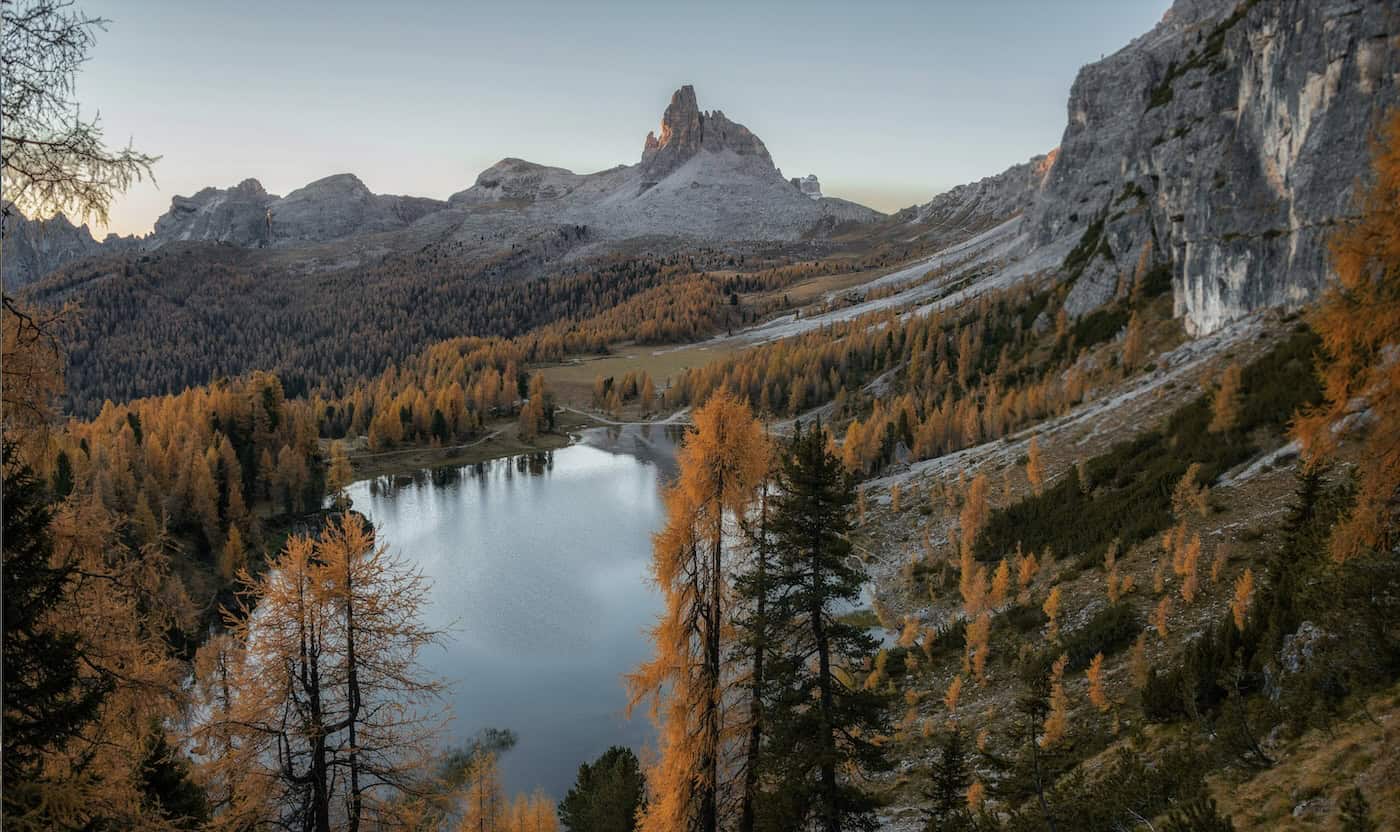 Scenic mountain landscape with lake, trees, and rocky peaks in fall colors.