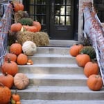 Decorative pumpkins and hay bales on front porch stairs for fall.