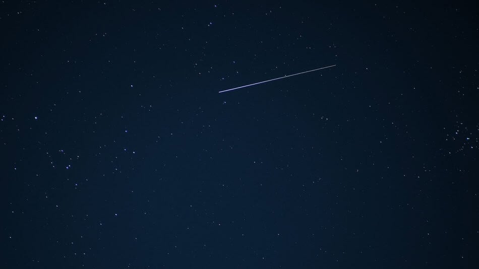 Night sky with shooting star during Perseid meteor shower.