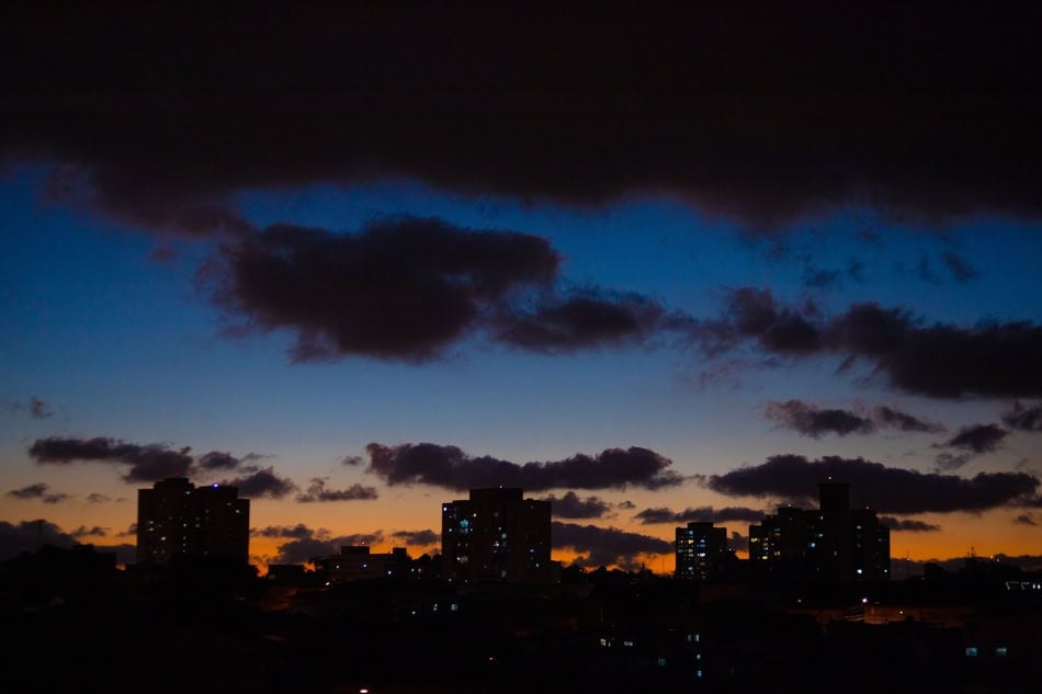 City skyline at dawn with dark clouds and early morning light.