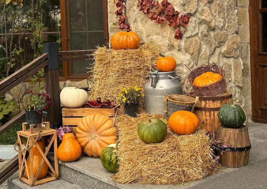 Decorative pumpkins and hay bales for Halloween front porch decor.