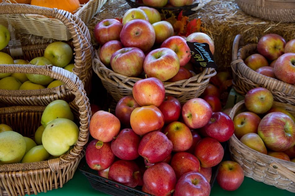 Variety of fresh apples in baskets at farmers' market.