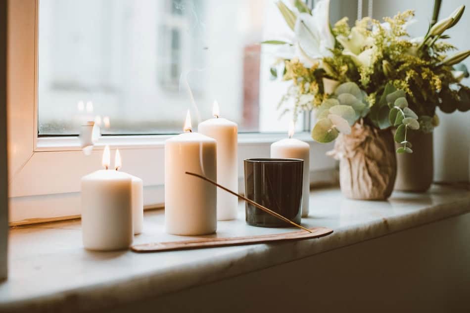 Decorative candles and flower arrangement on windowsill for cozy ambiance.
