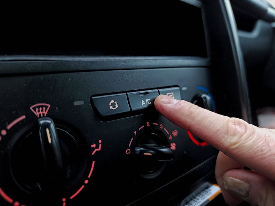 Person adjusting car air conditioning and defrost controls.