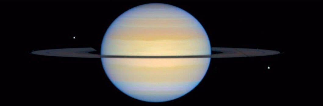 Saturn photographed by Hubble with its rings tilted only a few degrees from edge on, showing as a narrow band across the planet.