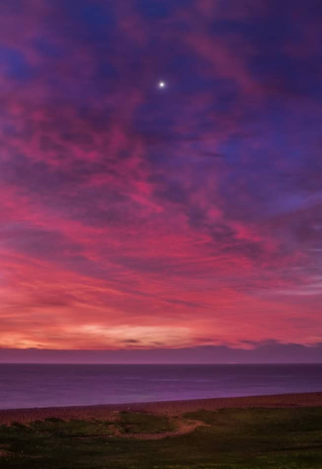 Bright Venus visible in colorful sunset sky over the ocean.