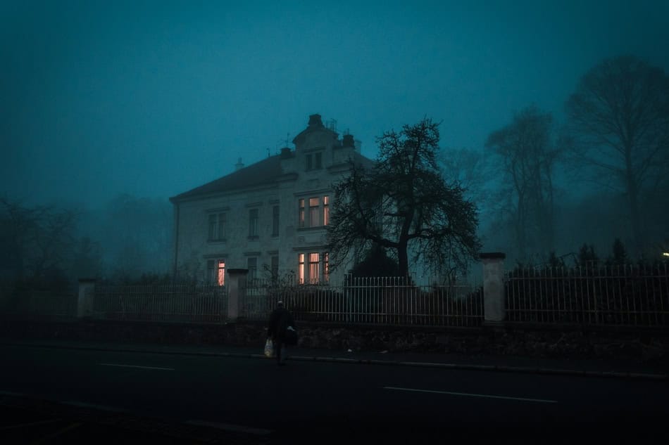 Spooky house with fog and dark trees, eerie atmosphere for Halloween.