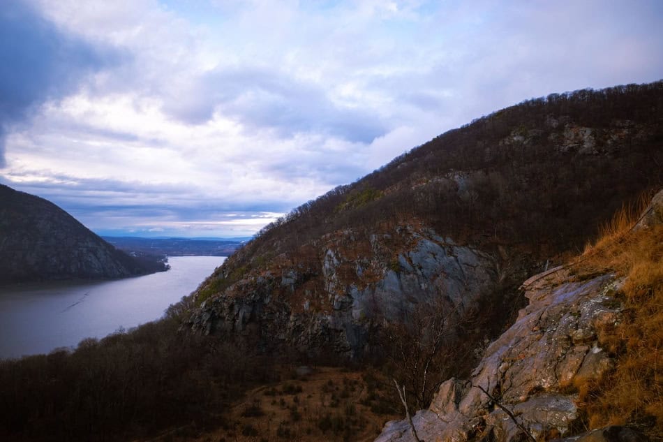 Beautiful mountain landscape with river and cloudy sky in the background.