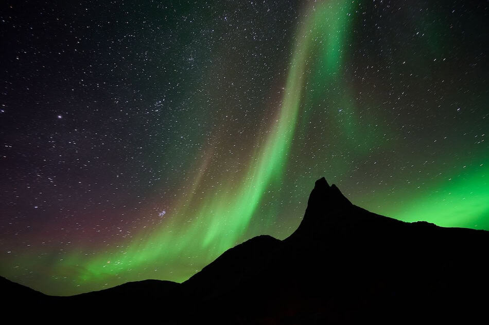 Spectacular aurora borealis lighting up the night sky over mountains.