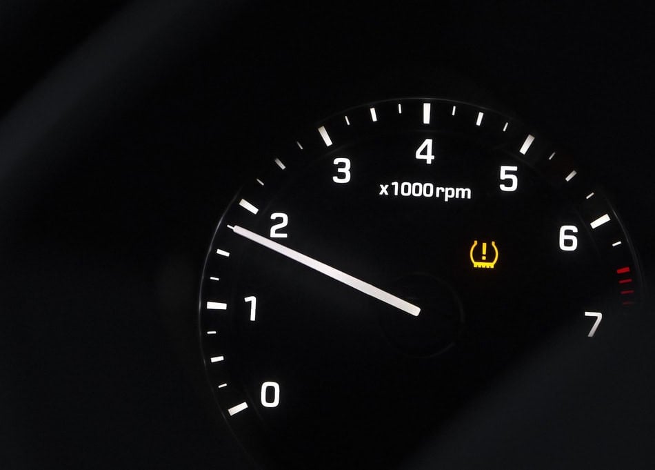 Car dashboard showing tire pressure warning light illuminated.