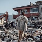 Person surveying destruction in earthquake-ravaged area.