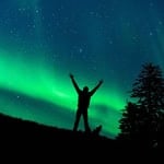 Person watching the northern lights under a starry sky.