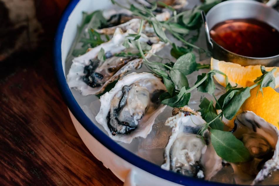 Fresh oysters served on ice with lemon and dipping sauce for seafood lovers.