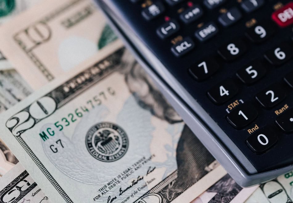 Calculator and cash on dollar bills for winter heating budget planning.