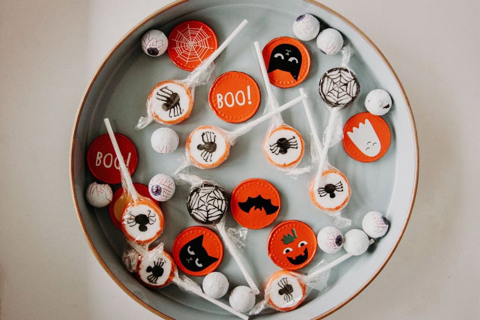 Halloween-themed lollipops and candy on a decorative plate for Halloween.