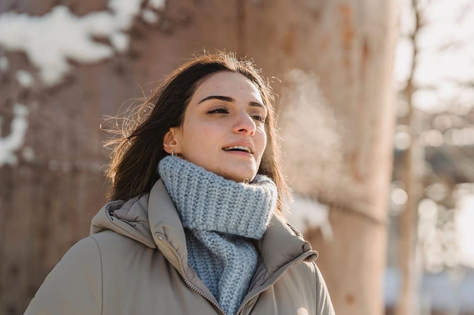 Woman exhaling visible breath on a cold day outdoors.
