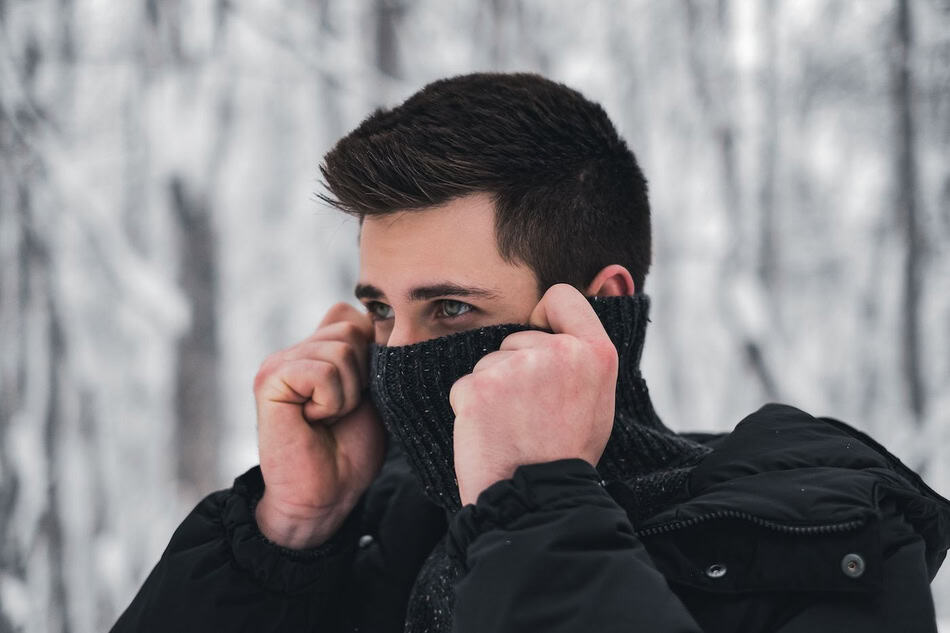 Man adjusting face mask in cold winter environment.