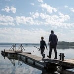 Father and son fishing on a peaceful lake dock during fall.