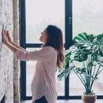 Woman inspecting wall insulation for winter heating efficiency.