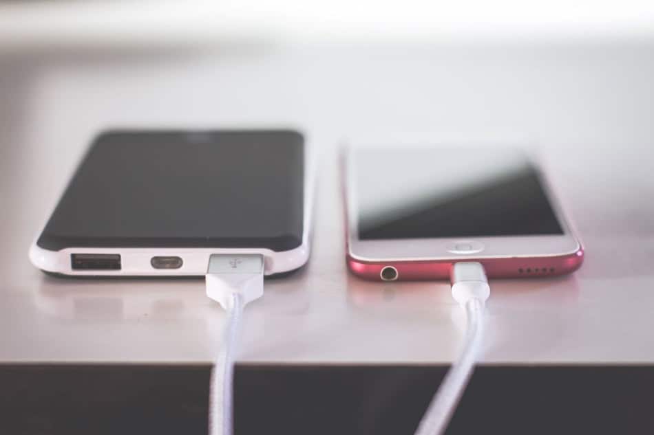 Smartphones connected to charging cables on a table.