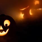 Carved Halloween pumpkin with glowing face and candles in the dark.