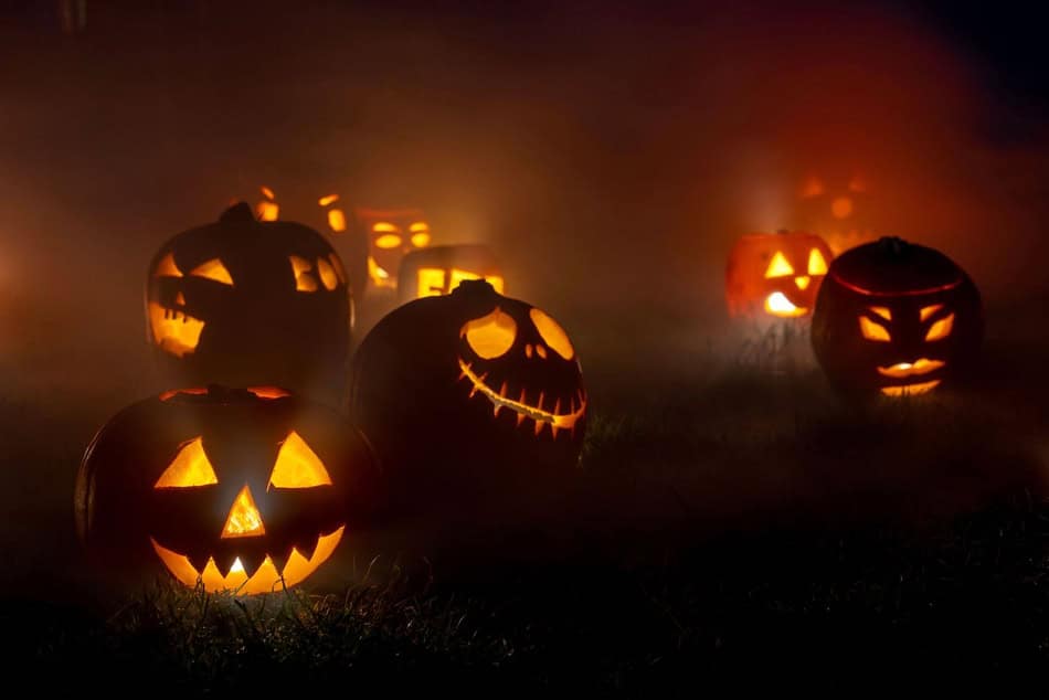 Spooky Halloween pumpkins with carved faces glowing in the dark.